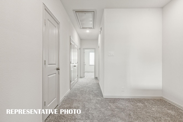 hall with baseboards, carpet, and attic access