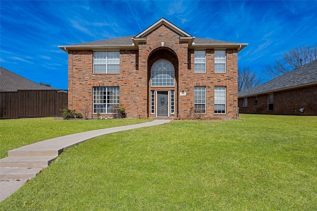 traditional-style home featuring fence, a front lawn, and brick siding