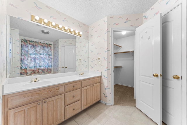 7632 Arbor Ridge Ct, Fort Worth, TX 76112 - bathroom with wallpapered walls, double vanity, a textured ceiling, tile patterned floors, and a spacious closet