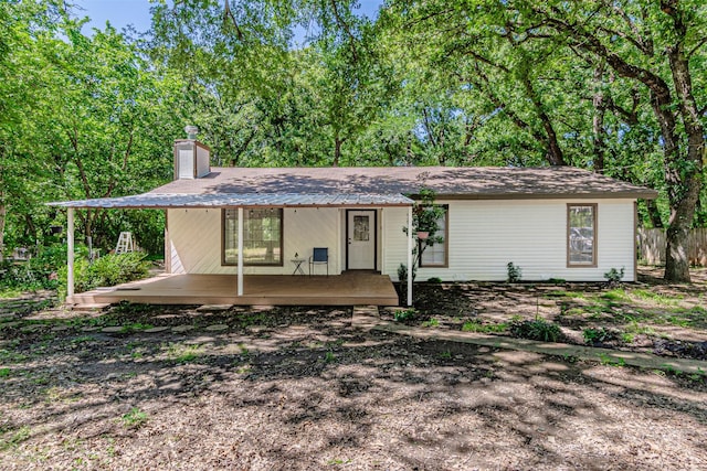 view of front of house featuring covered porch, fence, and a chimney