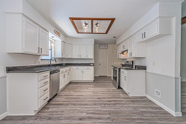 kitchen with stainless steel appliances, dark countertops, white cabinetry, and a sink