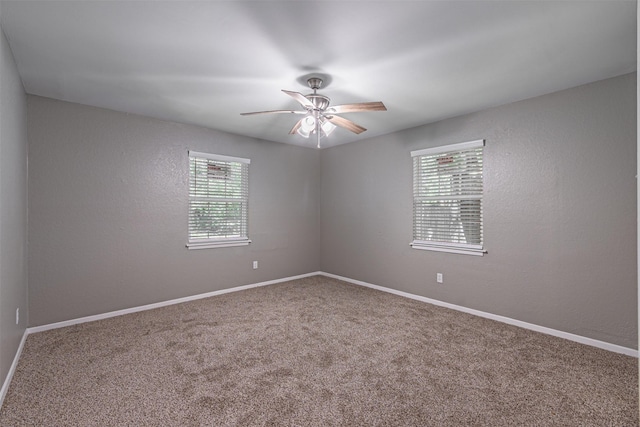 carpeted empty room featuring baseboards and a ceiling fan