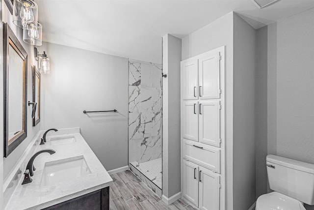full bath with toilet, a marble finish shower, a sink, and wood finished floors