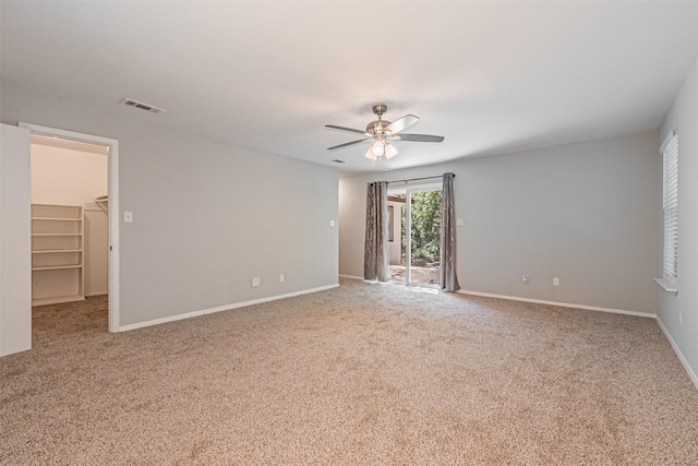 spare room featuring carpet floors, baseboards, a ceiling fan, and visible vents