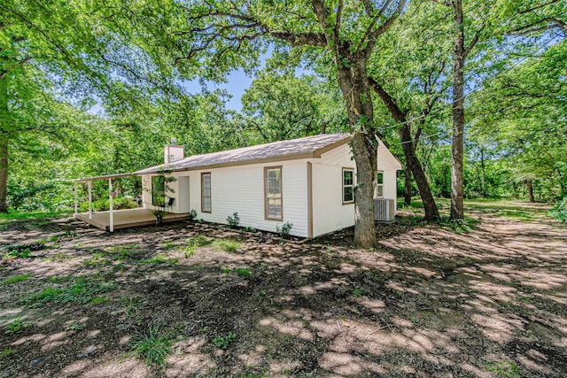 view of property exterior with a chimney, central AC unit, and a wooden deck