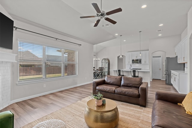 living area with visible vents, high vaulted ceiling, ceiling fan with notable chandelier, light wood finished floors, and recessed lighting