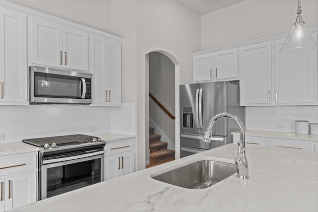 kitchen with a sink, white cabinets, pendant lighting, and stainless steel appliances