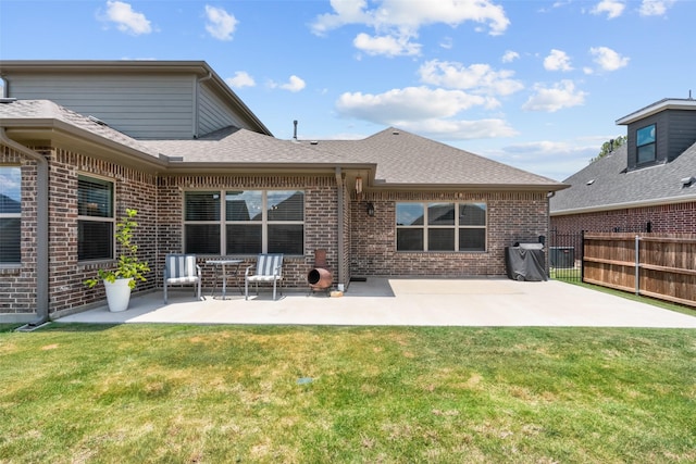 back of property with a patio, a yard, and brick siding