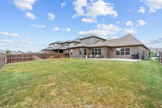 back of house with a yard, brick siding, a fenced backyard, and a patio area