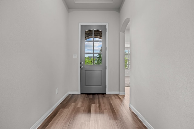 doorway to outside featuring baseboards, arched walkways, and dark wood finished floors