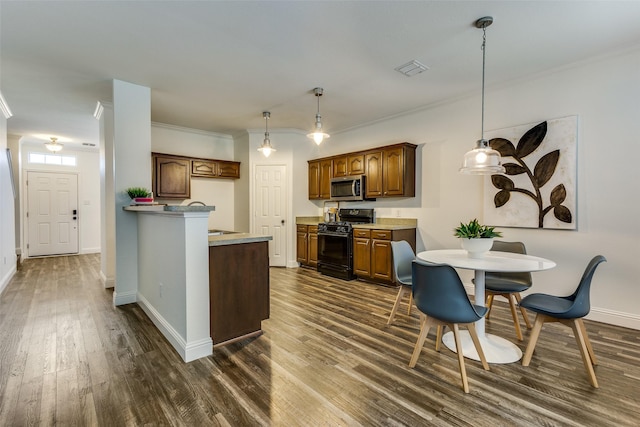 2416 Dogwood Dr, Little Elm, TX 75068 - kitchen with black gas range, stainless steel microwave, dark wood-style flooring, ornamental molding, and baseboards