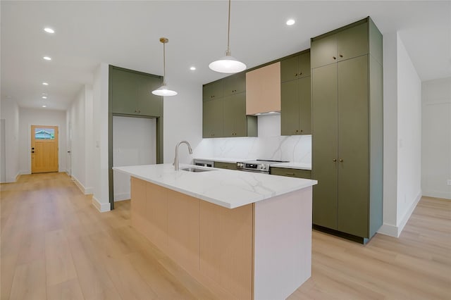 kitchen with baseboards, a sink, green cabinetry, and light wood finished floors