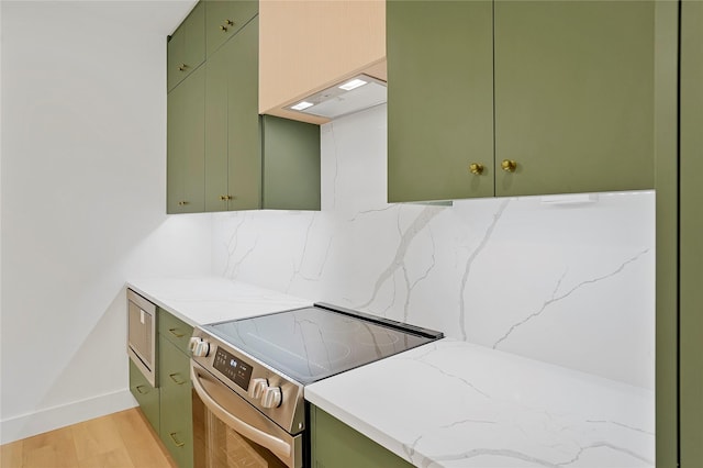 kitchen featuring green cabinetry, decorative backsplash, light wood-type flooring, and stainless steel range with electric cooktop