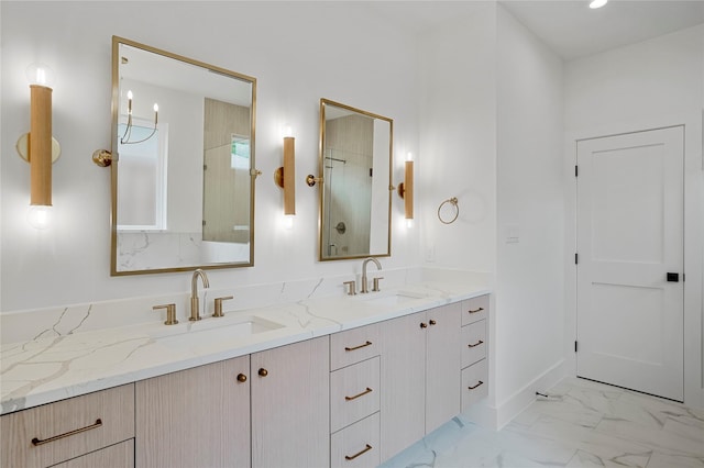 full bath featuring double vanity, marble finish floor, baseboards, and a sink