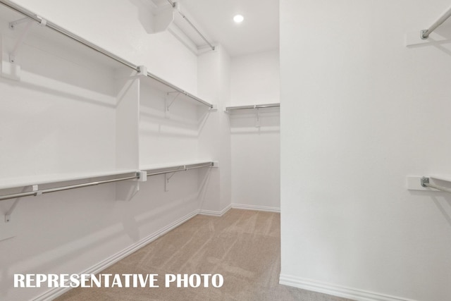 walk in closet featuring light colored carpet