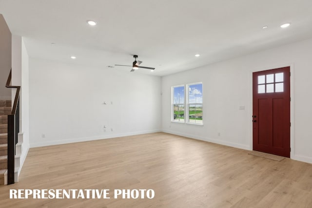 unfurnished living room featuring stairs, a healthy amount of sunlight, and light wood-style flooring