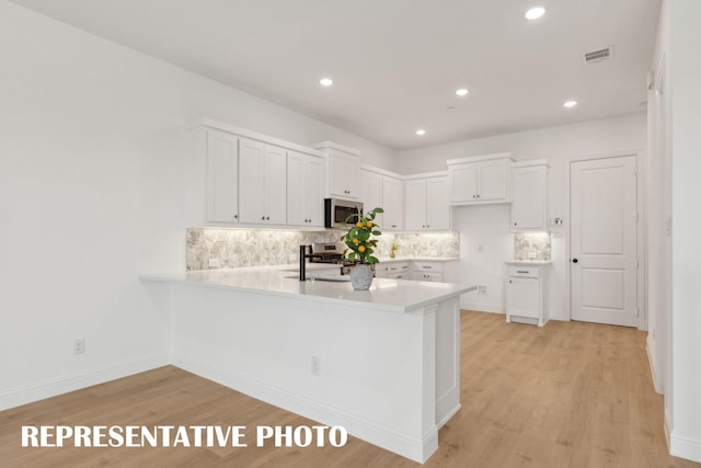 kitchen featuring decorative backsplash, visible vents, light countertops, a peninsula, and stainless steel appliances