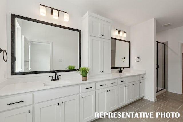 bathroom with double vanity, tile patterned floors, a sink, and a stall shower