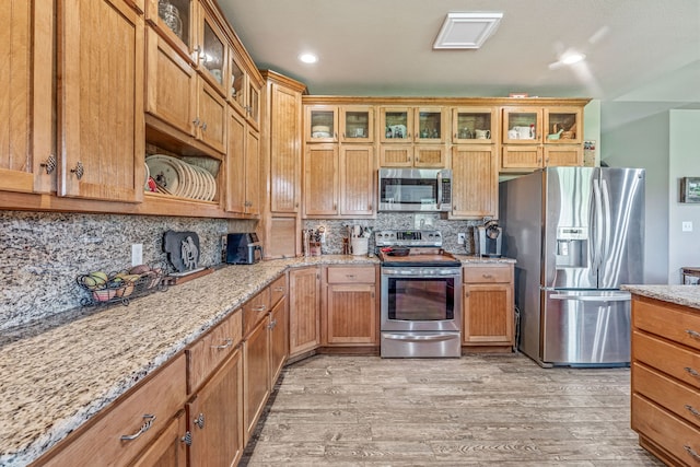 kitchen featuring stainless steel appliances, light stone counters, and light wood-style floors
