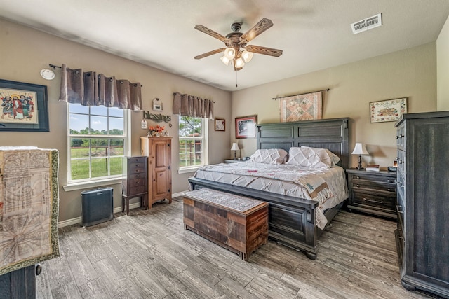 bedroom featuring visible vents, baseboards, ceiling fan, and wood finished floors