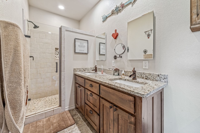 full bath with double vanity, a sink, a textured wall, and a shower stall