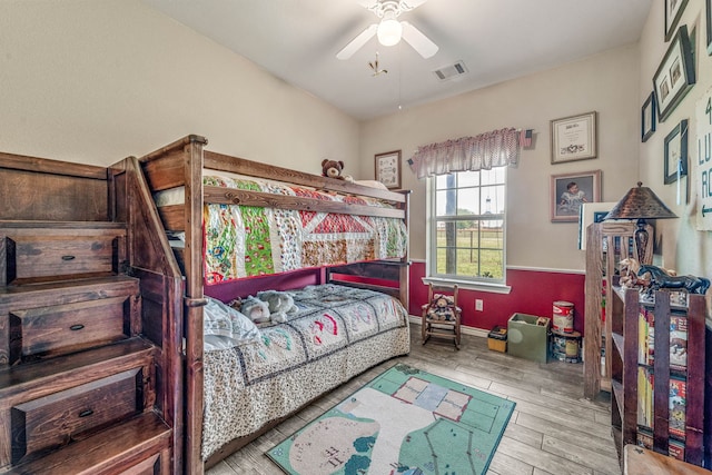 bedroom featuring baseboards, a ceiling fan, wood finished floors, and visible vents