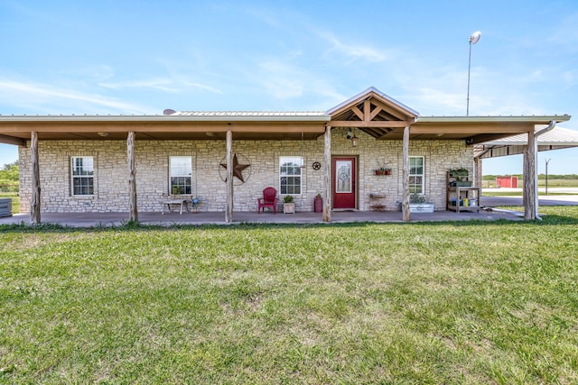 view of front facade with a patio area, a front lawn, and stone siding
