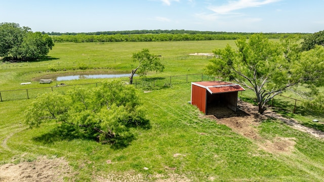 view of yard with fence, an outbuilding, a water view, and a rural view