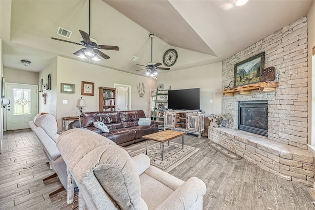 living room featuring visible vents, a fireplace, wood finished floors, and high vaulted ceiling