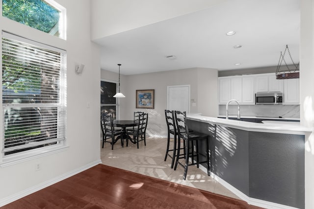 907 Ozark Dr, Allen, TX 75002 - kitchen featuring light countertops, stainless steel microwave, a breakfast bar, recessed lighting, and white cabinetry