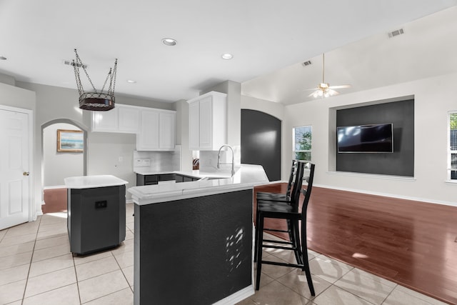 907 Ozark Dr, Allen, TX 75002 - kitchen featuring a kitchen island, arched walkways, light tile patterned floors, a sink, and light countertops