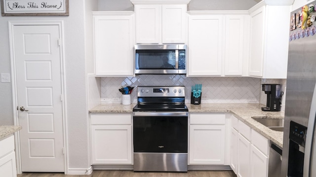 kitchen with light stone counters, appliances with stainless steel finishes, tasteful backsplash, and white cabinetry