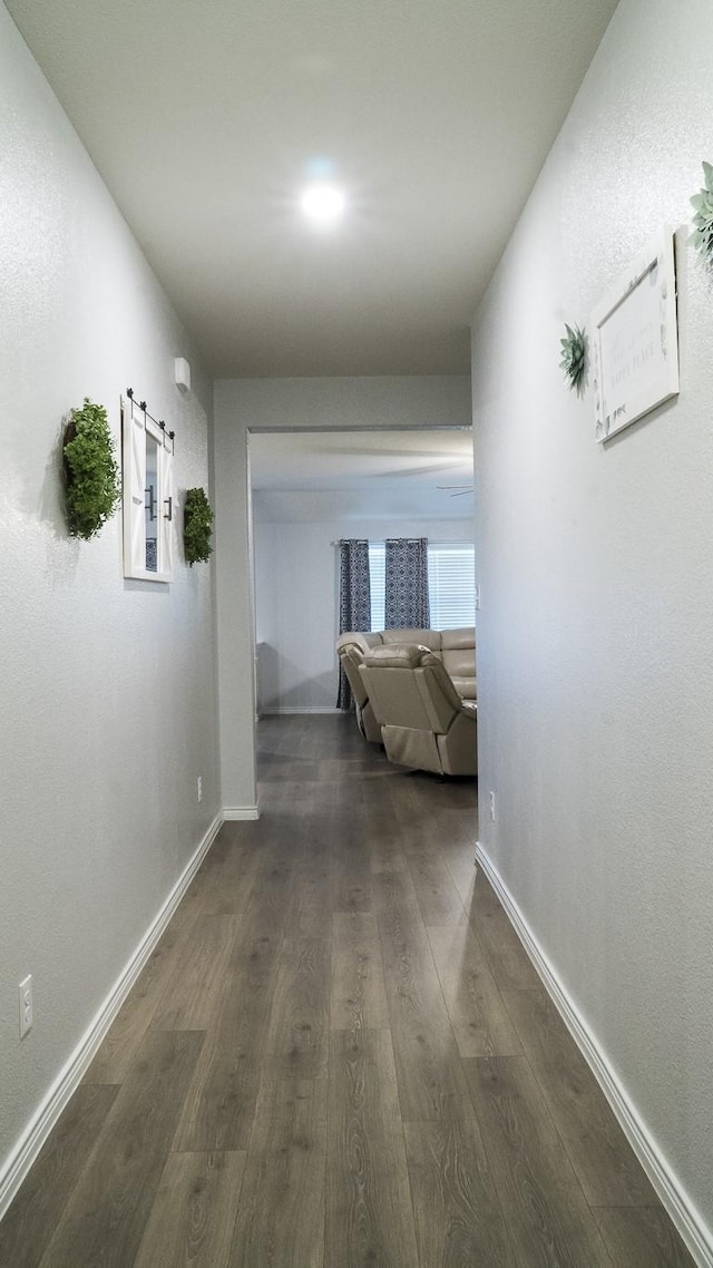 hallway featuring baseboards and dark wood-style floors