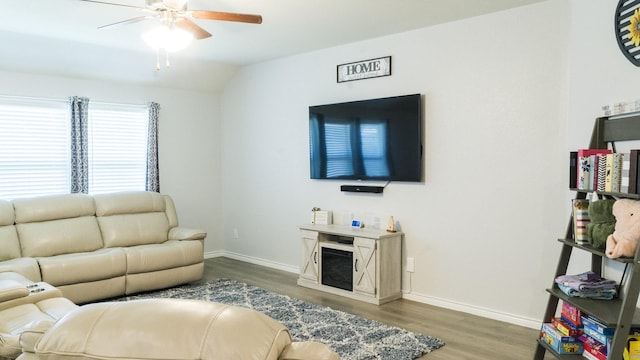 living area with baseboards, ceiling fan, wood finished floors, and vaulted ceiling