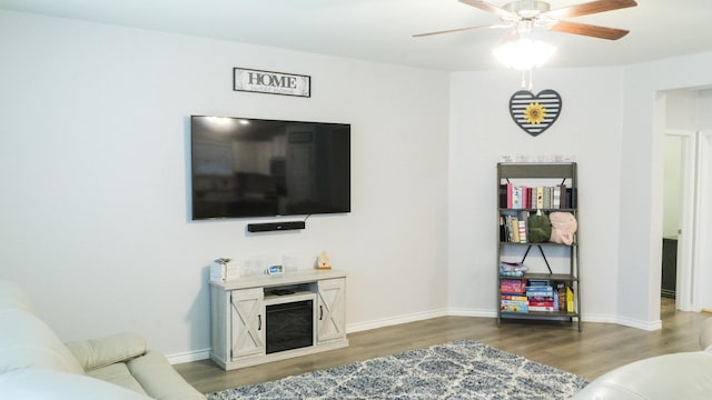 living area featuring baseboards, a ceiling fan, and wood finished floors