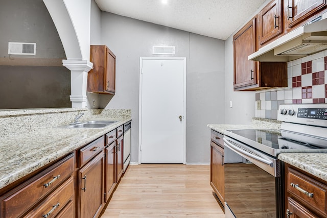 kitchen with a sink, stainless steel range with electric stovetop, decorative backsplash, under cabinet range hood, and visible vents
