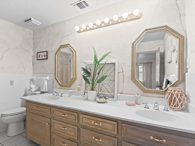 12580 Briar Rd, Azle, TX 76020 - full bathroom with double vanity, tile walls, toilet, a textured ceiling, and tile patterned flooring