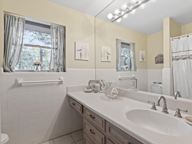 12580 Briar Rd, Azle, TX 76020 - full bath with toilet, tile patterned floors, tile walls, vanity, and a wainscoted wall