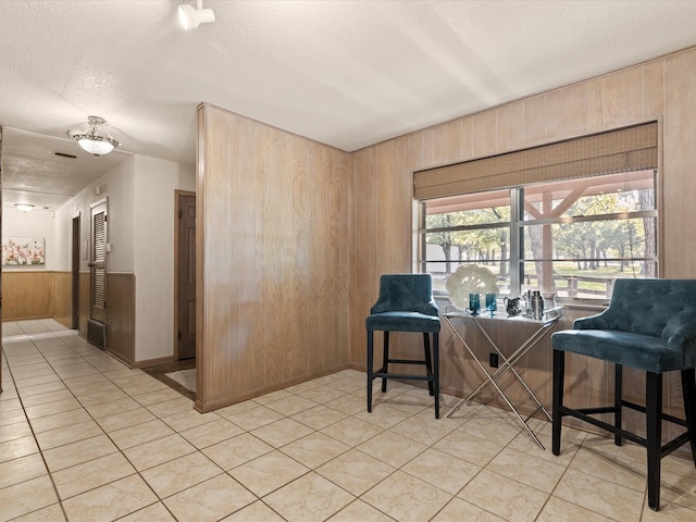 12580 Briar Rd, Azle, TX 76020 - sitting room with wooden walls, a textured ceiling, and light tile patterned floors