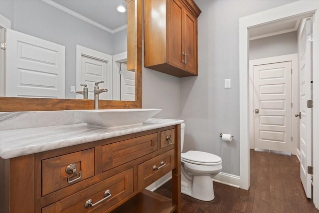bathroom with crown molding, wood finished floors, vanity, baseboards, and toilet