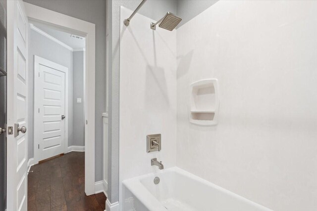 bathroom featuring visible vents, bathtub / shower combination, baseboards, ornamental molding, and hardwood / wood-style floors