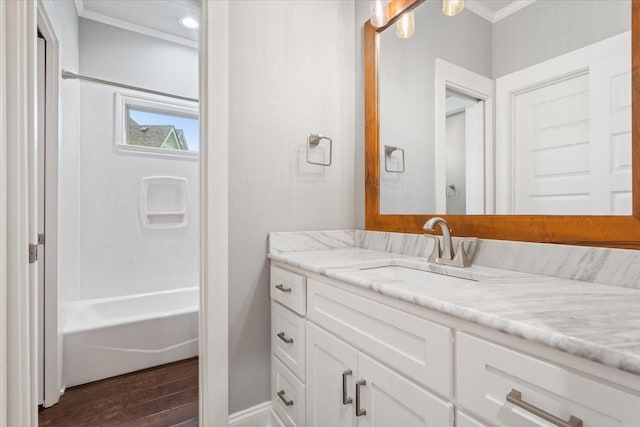 bathroom with crown molding, washtub / shower combination, vanity, baseboards, and wood finished floors