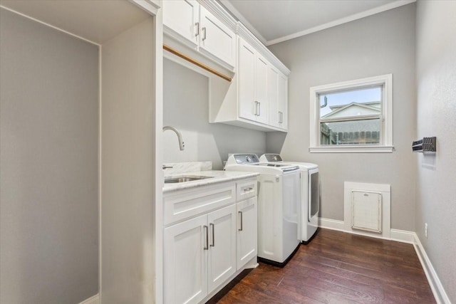 washroom with washing machine and clothes dryer, cabinet space, a sink, baseboards, and dark wood-style floors