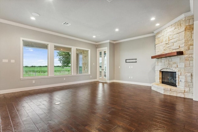 unfurnished living room featuring a stone fireplace, crown molding, dark wood-style floors, and visible vents