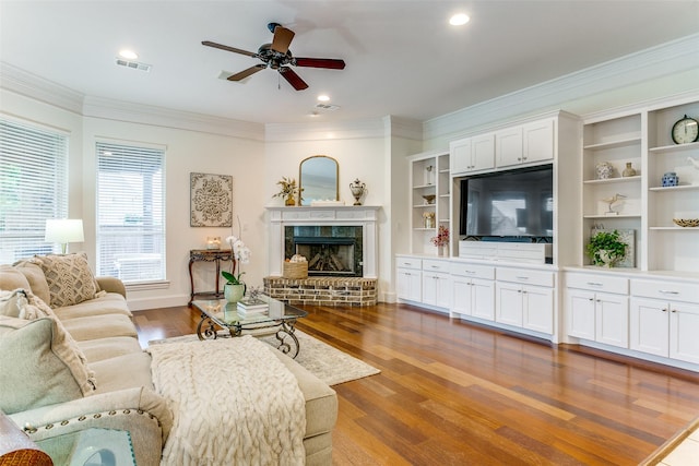 living area featuring a ceiling fan, visible vents, ornamental molding, and wood finished floors