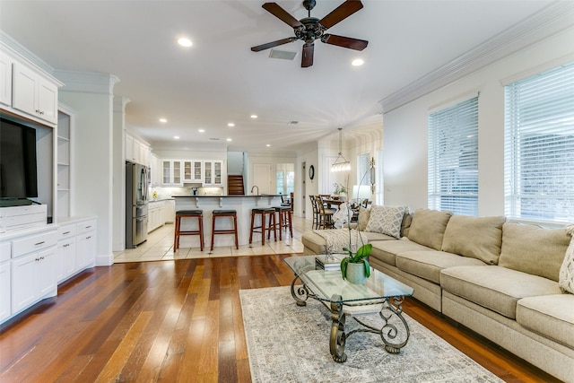 living room featuring ornamental molding, wood-type flooring, a ceiling fan, and recessed lighting