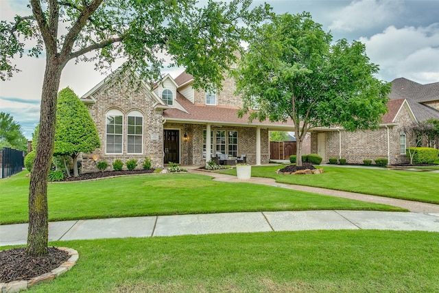 view of front of house featuring brick siding, fence, a shingled roof, and a front yard