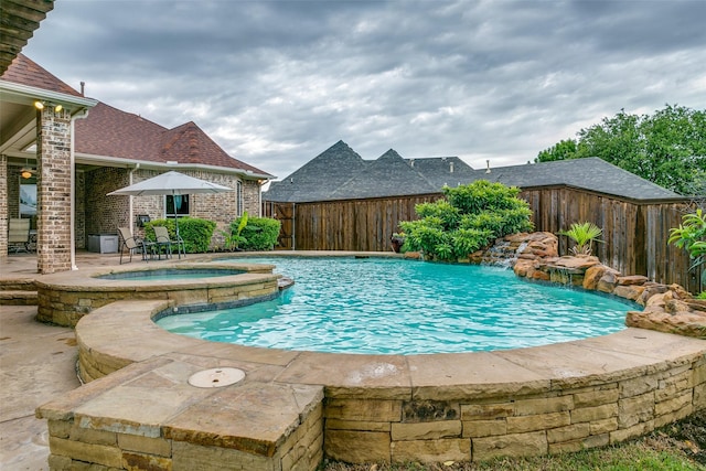view of swimming pool featuring a pool with connected hot tub, a fenced backyard, and a patio area