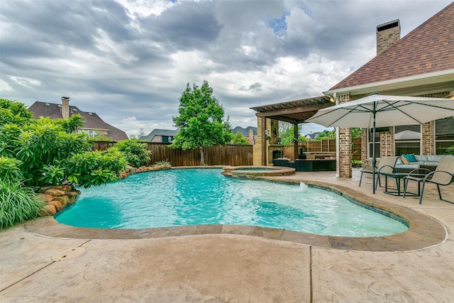 view of swimming pool featuring a patio, a fenced backyard, and a pool with connected hot tub