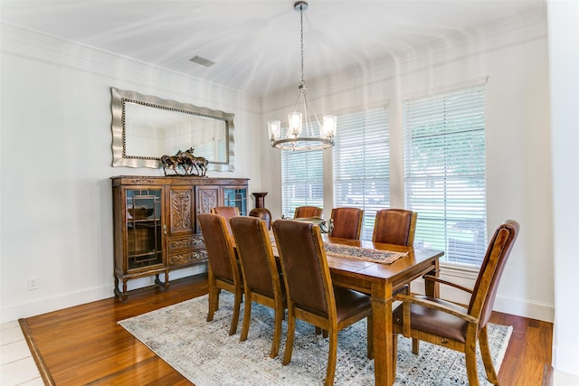 dining area featuring baseboards, crown molding, wood finished floors, and a notable chandelier
